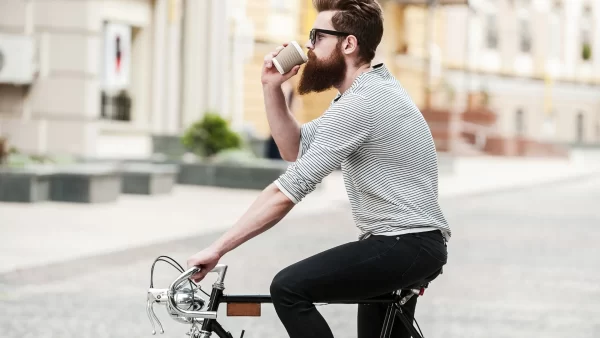 Man riding a bike while drinking a coffee