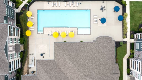 Aerial view of the swimming pool, expansive sun deck, and the apartments at The Pointe at Five Oaks